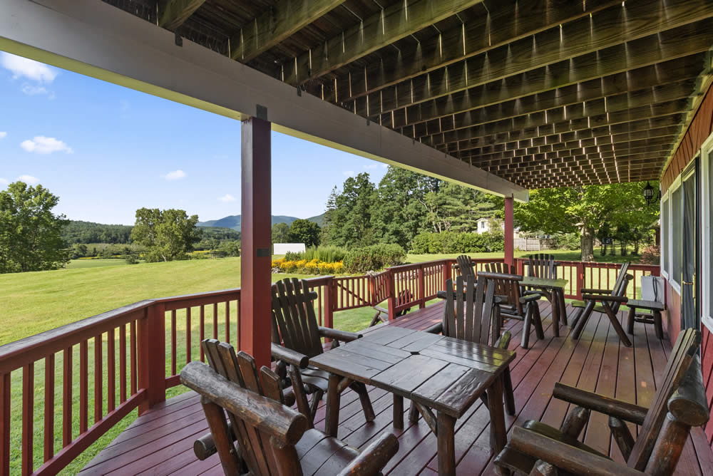 lodge deck with chairs, tables and a lovely lawn view
