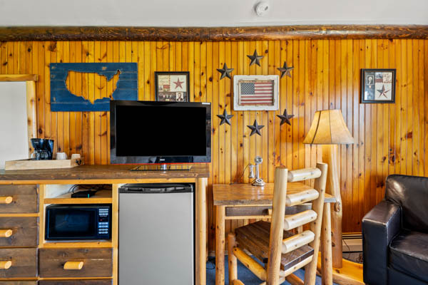 Guest room with TV, fridge, and desk with chair.