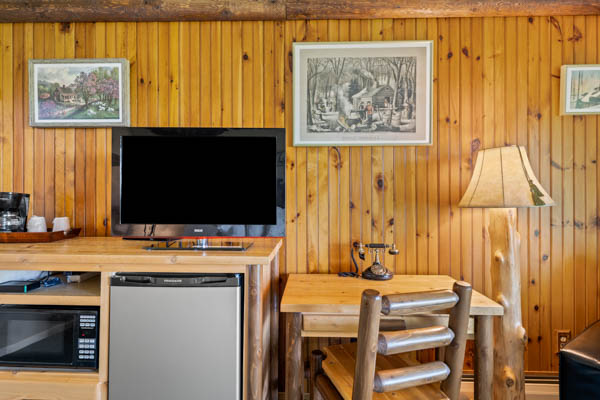 Guest room with TV, fridge, and desk with chair.