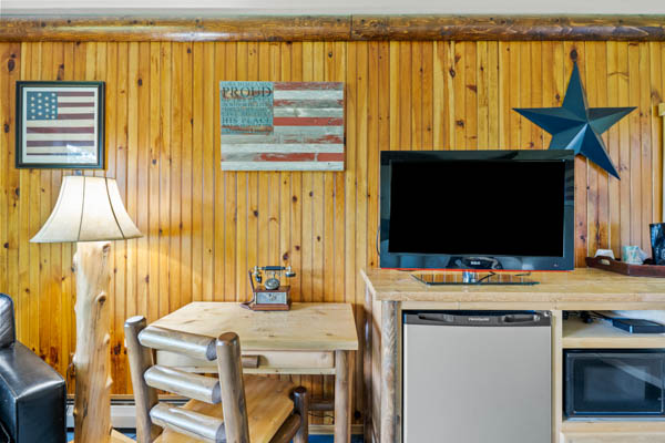 guest room with desk, TV and fridge.