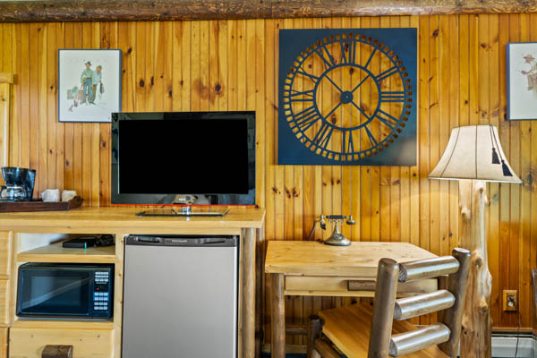 Guest room with TV, fridge, and desk with chair.