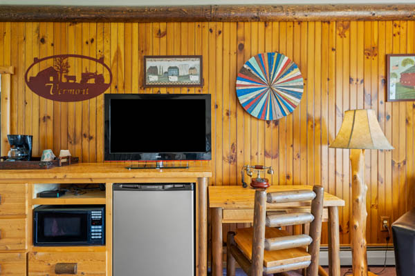 Guest room with TV, fridge, and desk with chair.