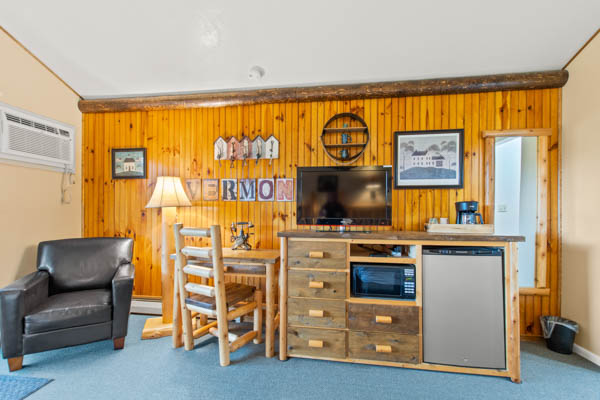 Guest room with TV, fridge, and comfy chair.