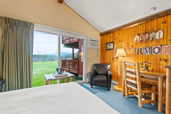 Guest room with two double beds, TV, fridge, and comfy chair.