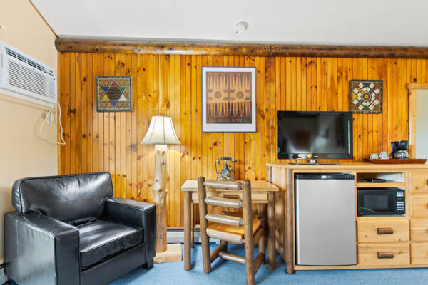 Guest room with TV, fridge, and comfy chair.