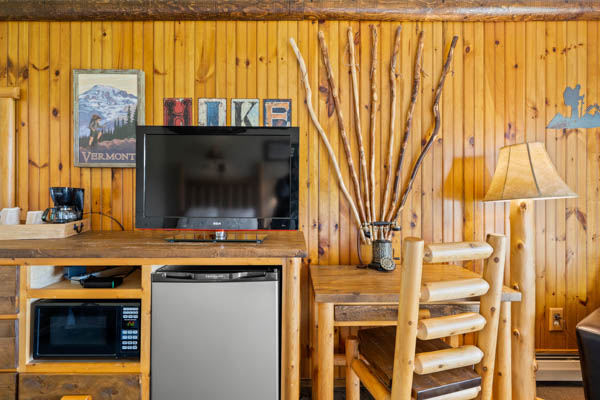 Guest room with TV, fridge, and desk with chair.