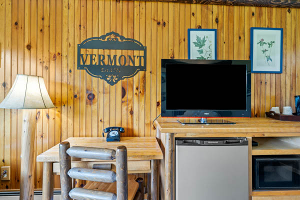 Room with desk, tv, and fridge built in.