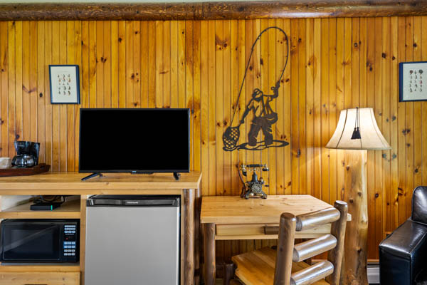 Guest room with TV, fridge, and desk with chair.