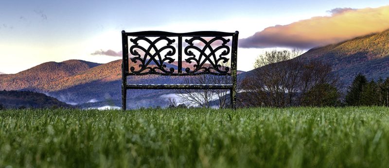 a lovely vermont scene with chair in foreground and fall adorned rolling hills in the background